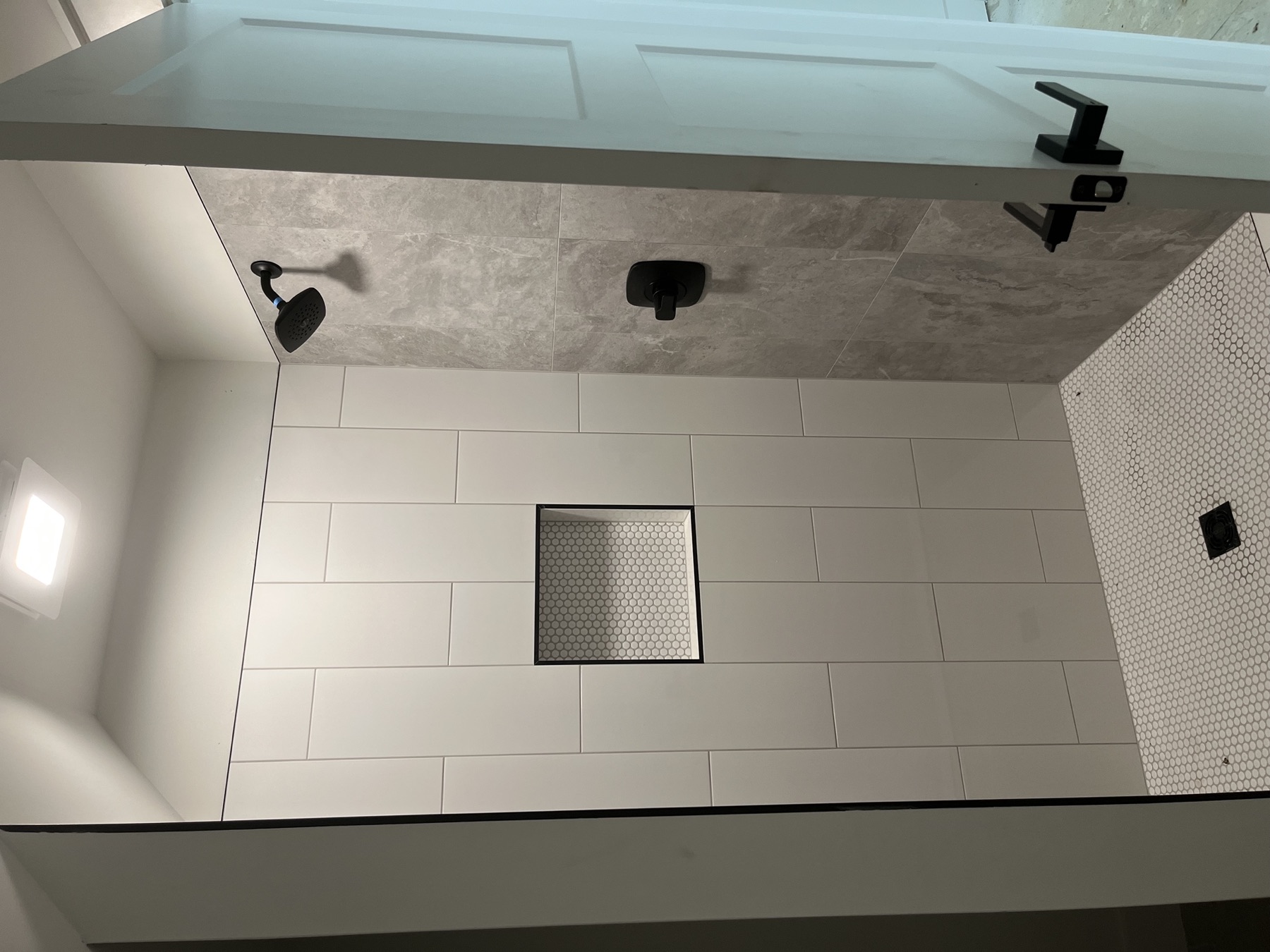 Walk-in shower with white tile and hex floor